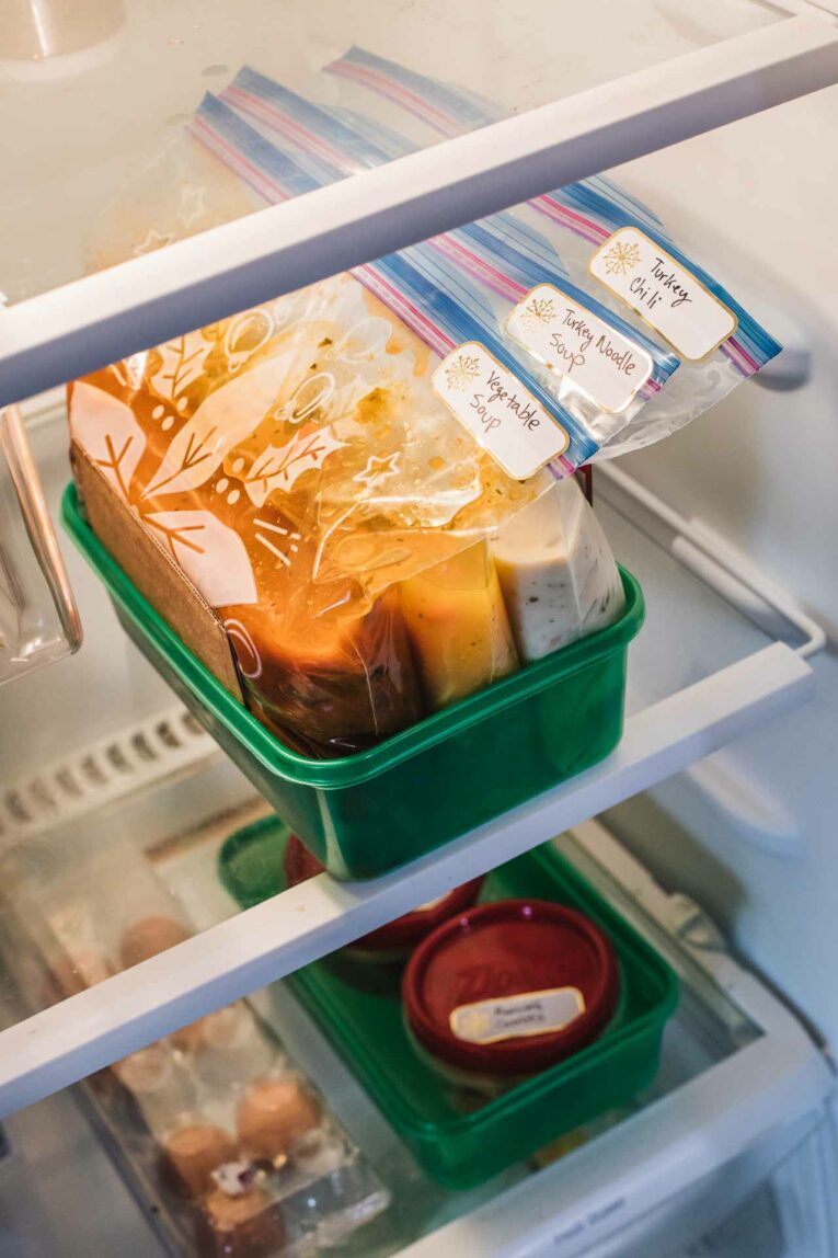 Freezer bags in a green Ziploc container with Thanksgiving leftovers organized into recipes.