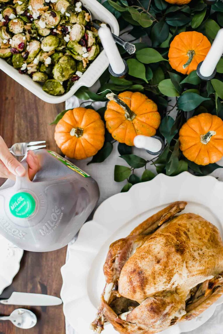 Top view of Thanksgiving tablescape on a wood table with pumpkins, greenery, and candles.