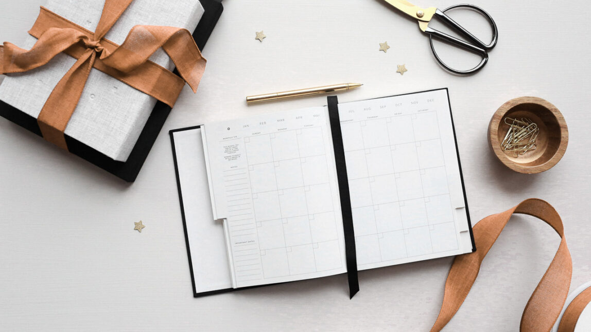Holiday planner on a white table with gift boxes.