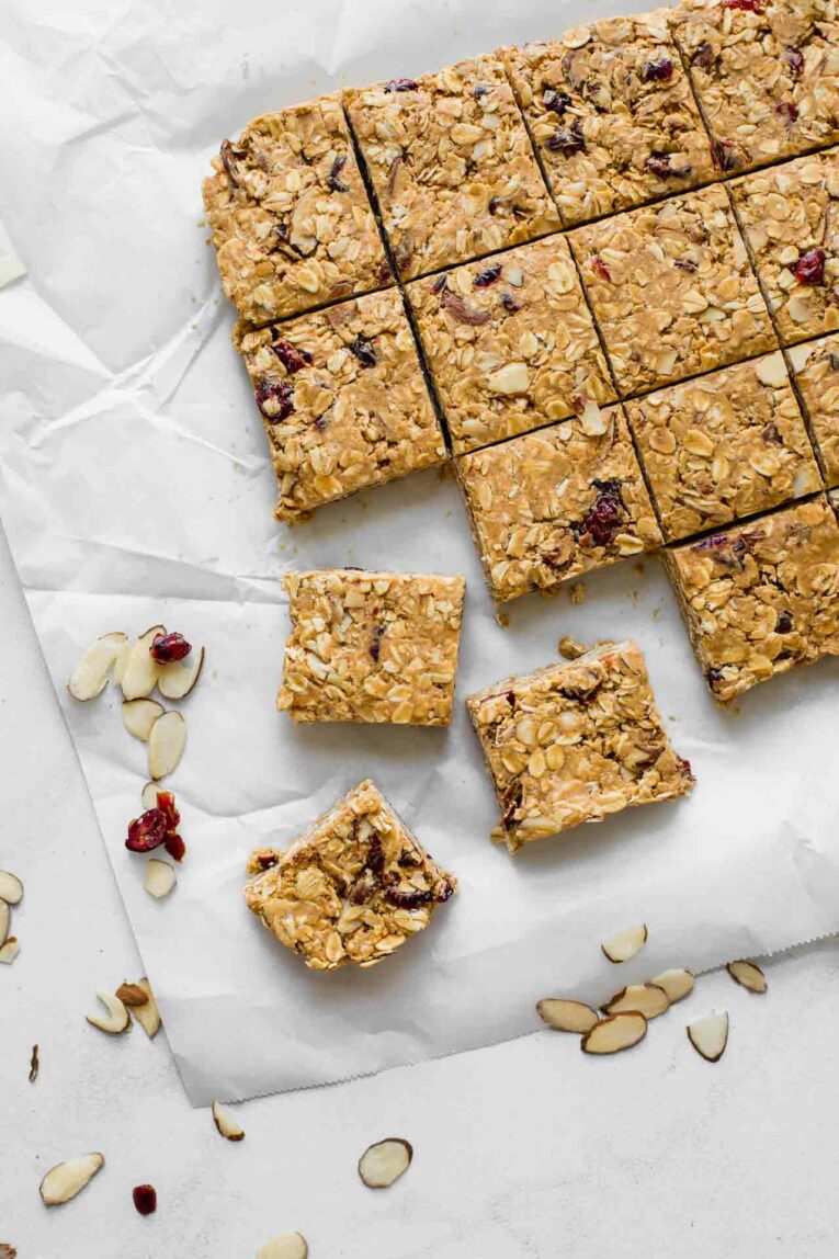 Cranberry Almond Healthy Oatmeal Bars on parchment paper with sliced almonds and dried cranberries.