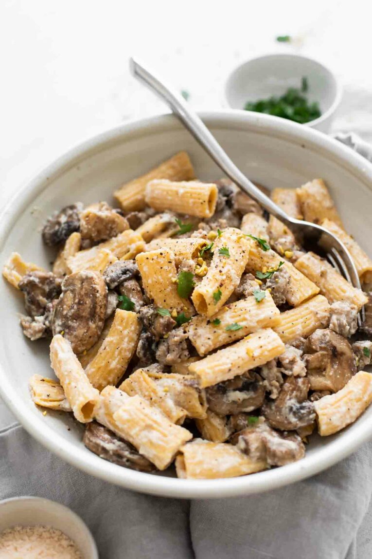 Angle shot of Creamy Mushroom & Sausage Rigatoni in a bowl with a fork.