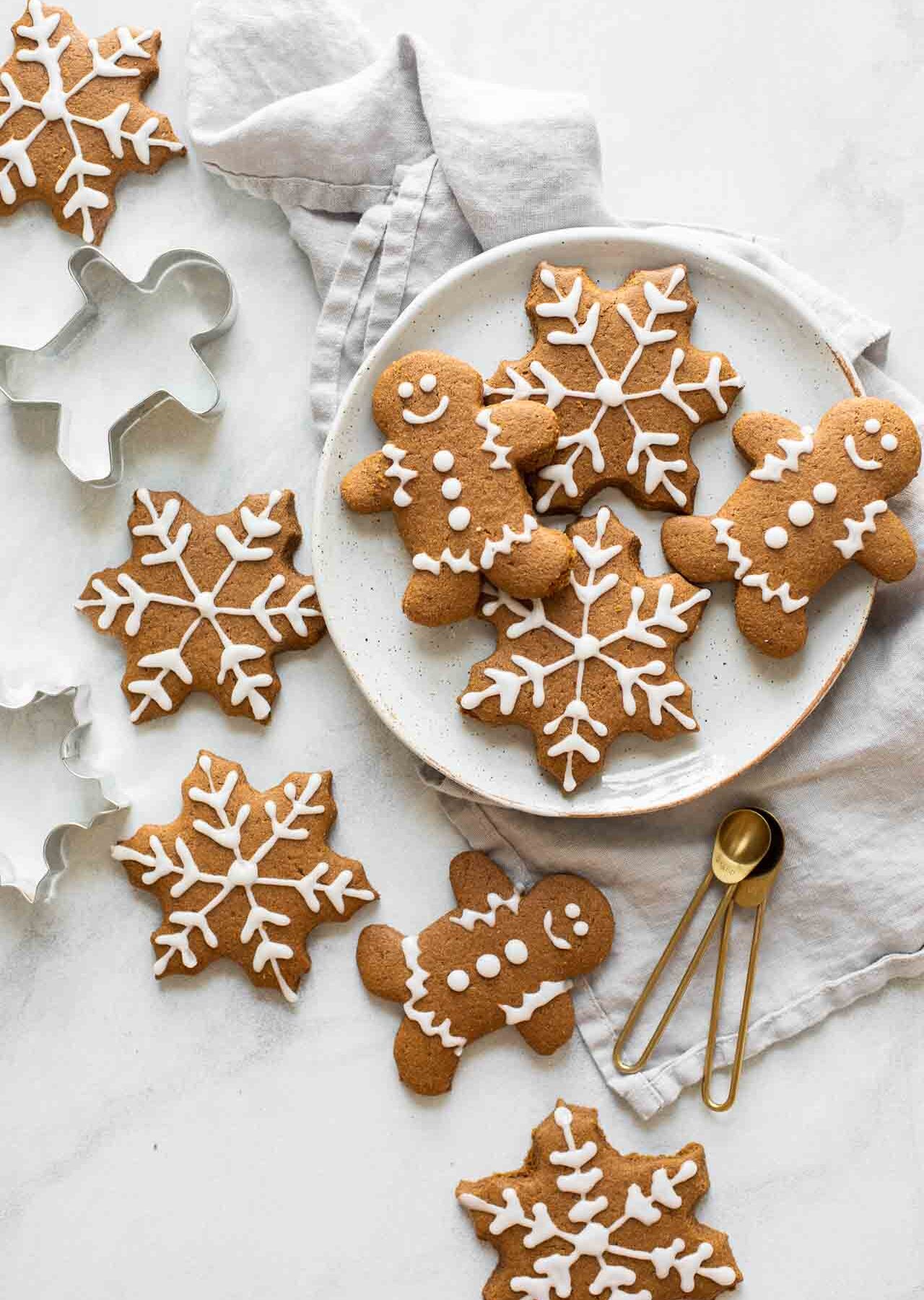 Gingerbread cookies spread across a marble countertop with cookie cutters and a plate.
