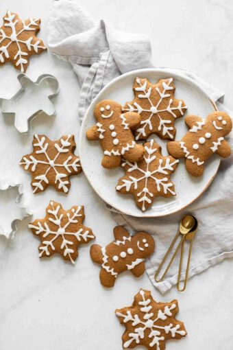 Gingerbread cookies spread across a marble countertop with cookie cutters and a plate.
