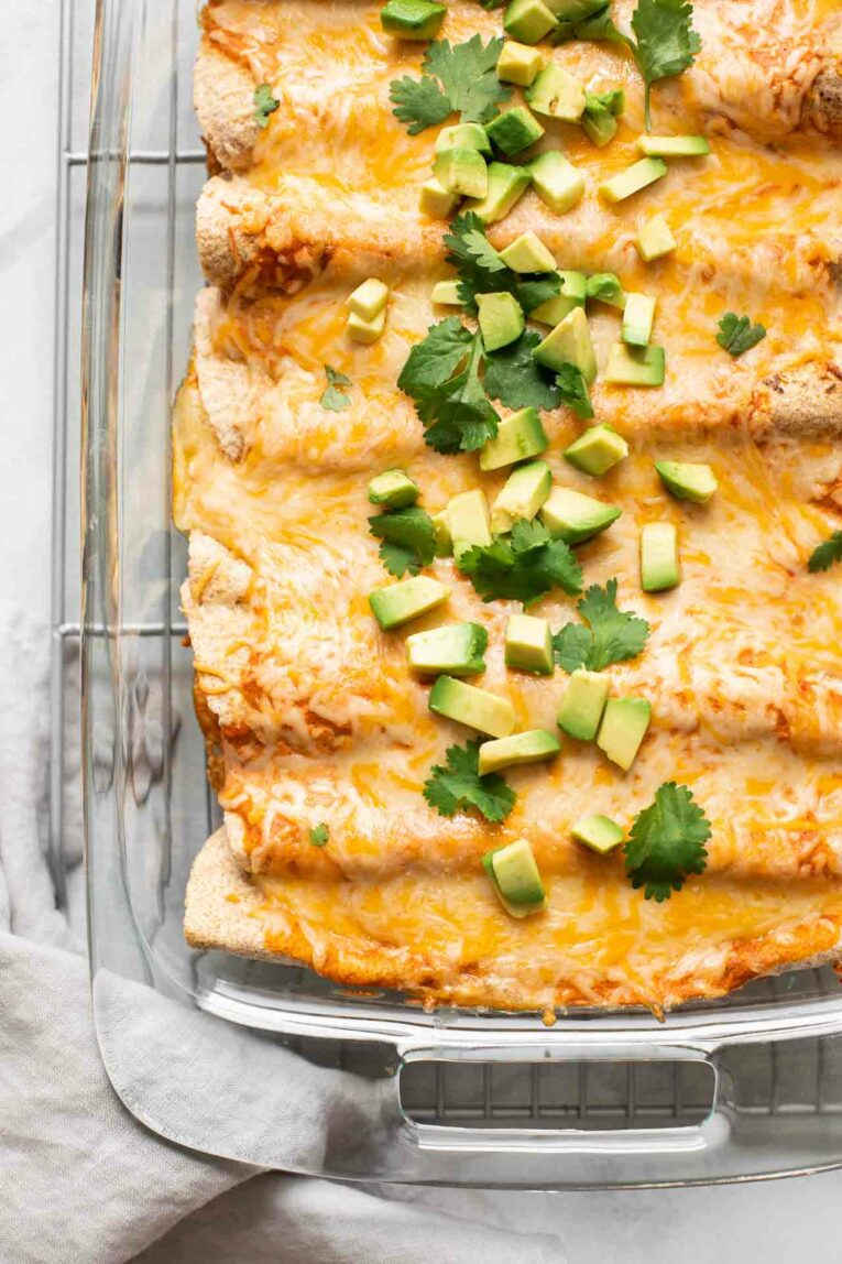 Close up of vegetarian enchiladas topped with cilantro and avocado.