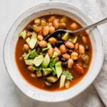 Top shot of vegan chili with avocado in a white bowl with a spoon.
