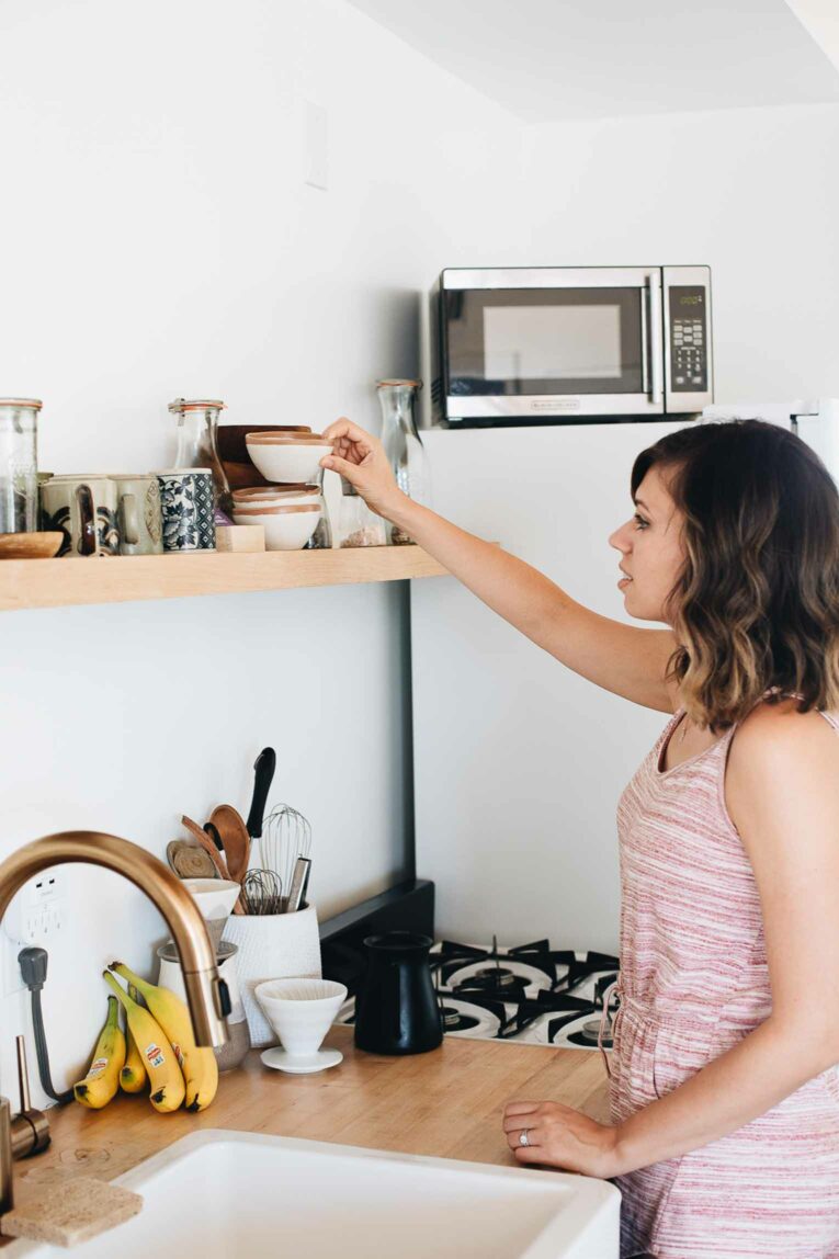 Woman organizing kitchen shelf.
