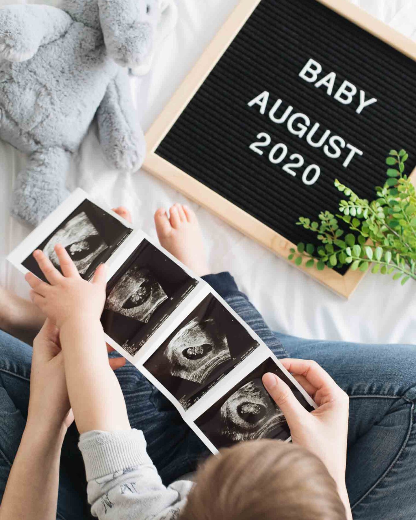 Top shot of mom and toddler holding sonogram for baby announcement.