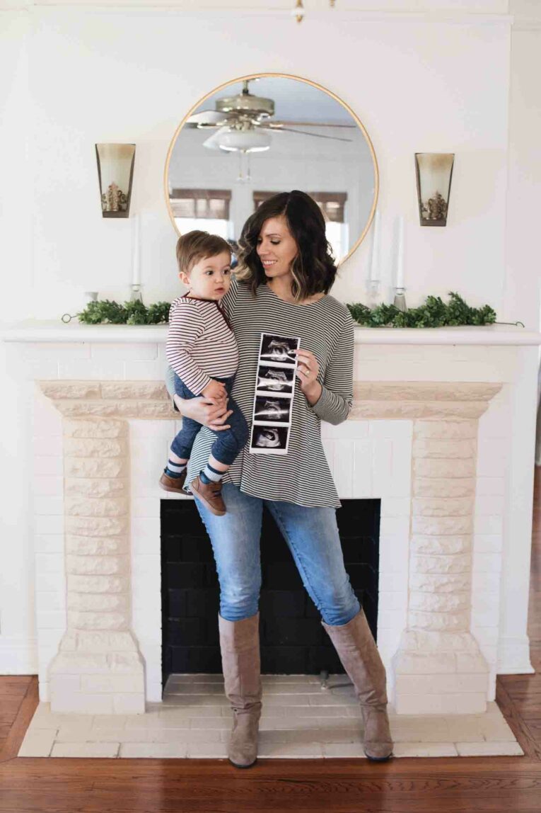 Mom and toddler holding sonogram to announce new baby.