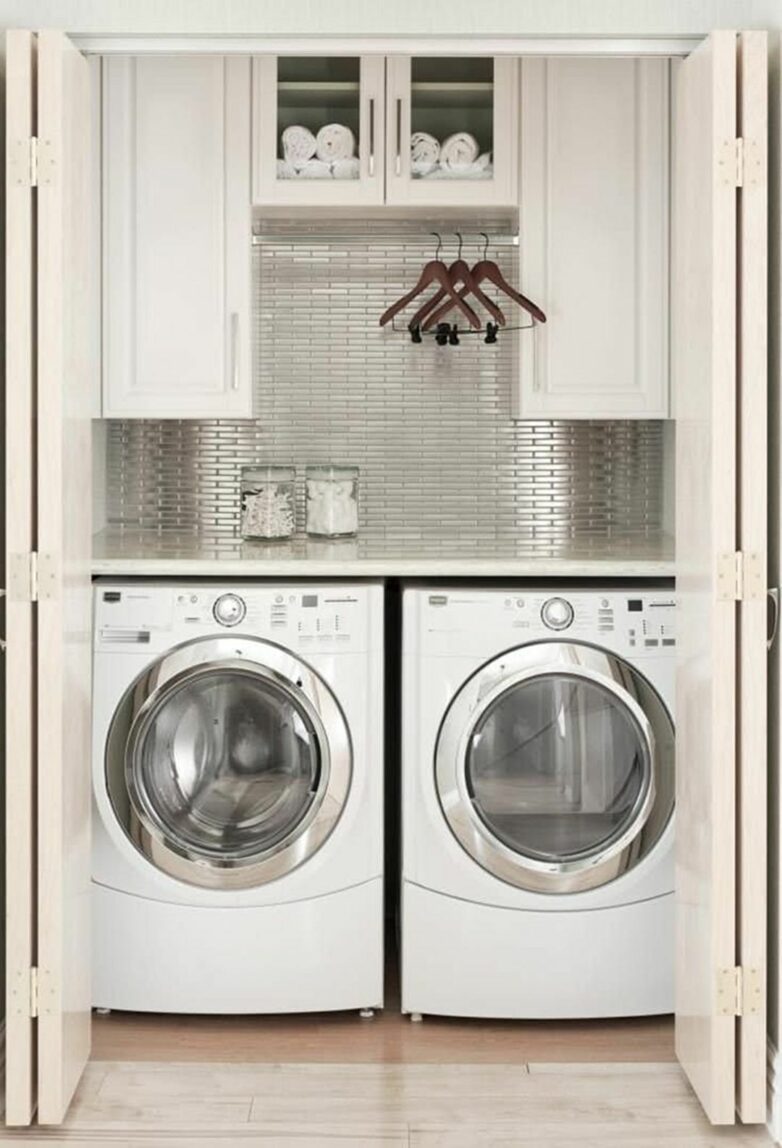 Small laundry closet with washer, dryer, white counter top, and silver backsplash. 