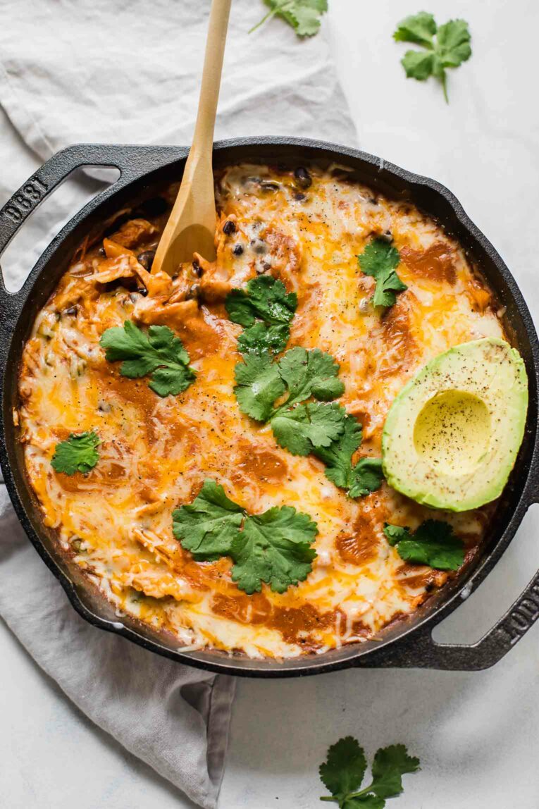 Top shot of Creamy Healthy Chicken Enchilada Skillet with a spoon and topped with cilantro and avocado.