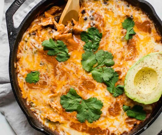Top shot of Creamy Healthy Chicken Enchilada Skillet with a spoon and topped with cilantro and avocado.