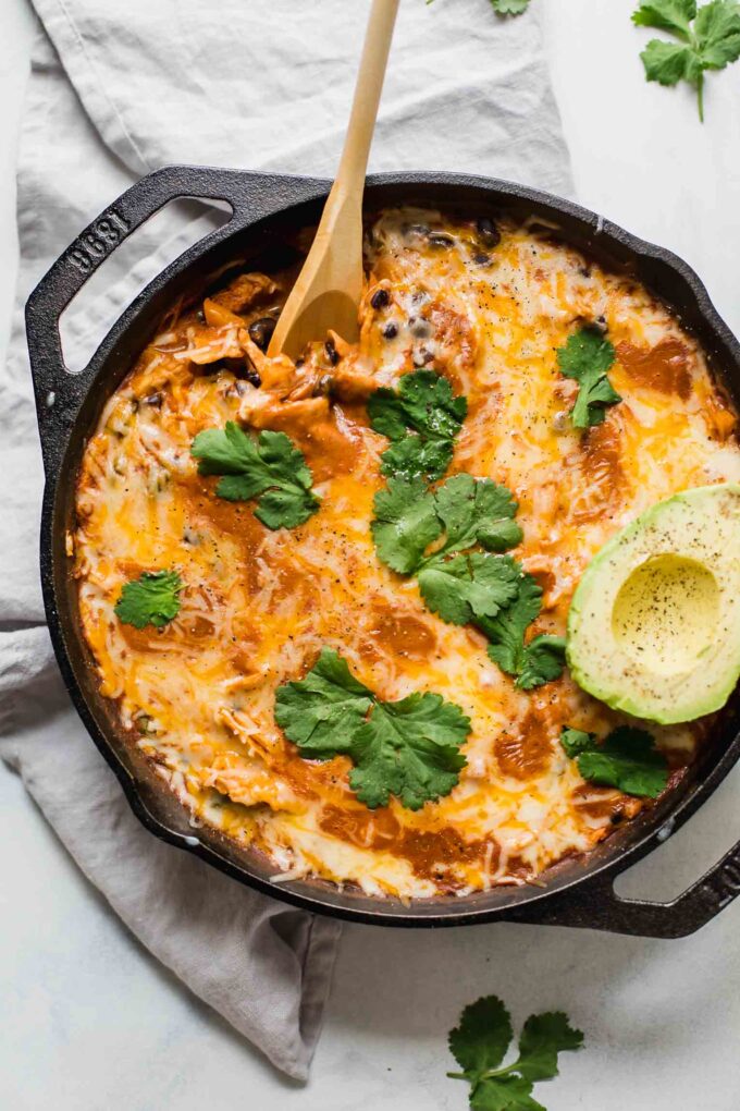 Top shot of Creamy Healthy Chicken Enchilada Skillet with a spoon and topped with cilantro and avocado.