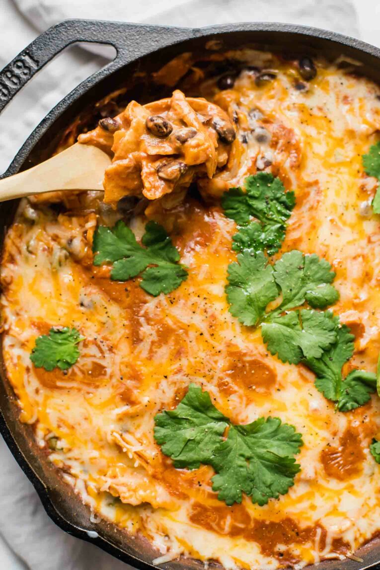 Close up of chicken enchilada casserole in a skillet.