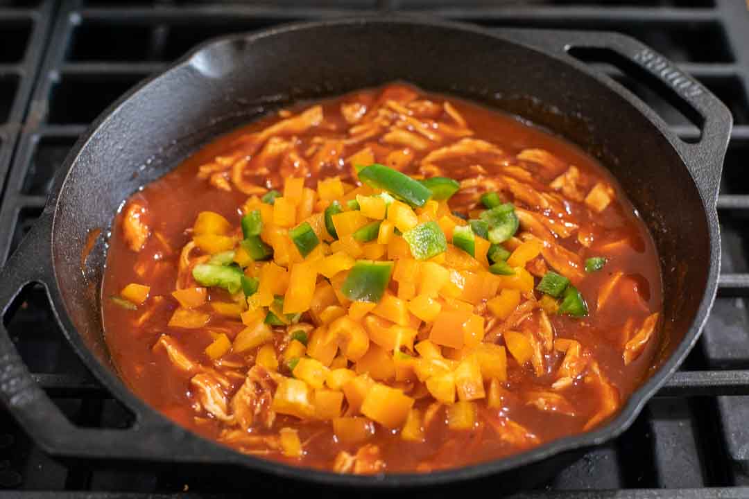 Bell peppers added to shredded chicken and enchilada sauce.