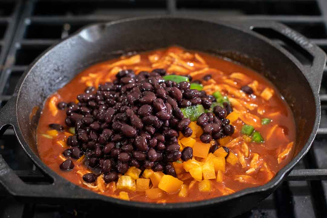 Black beans added to diced peppers, chicken, and enchilada sauce.