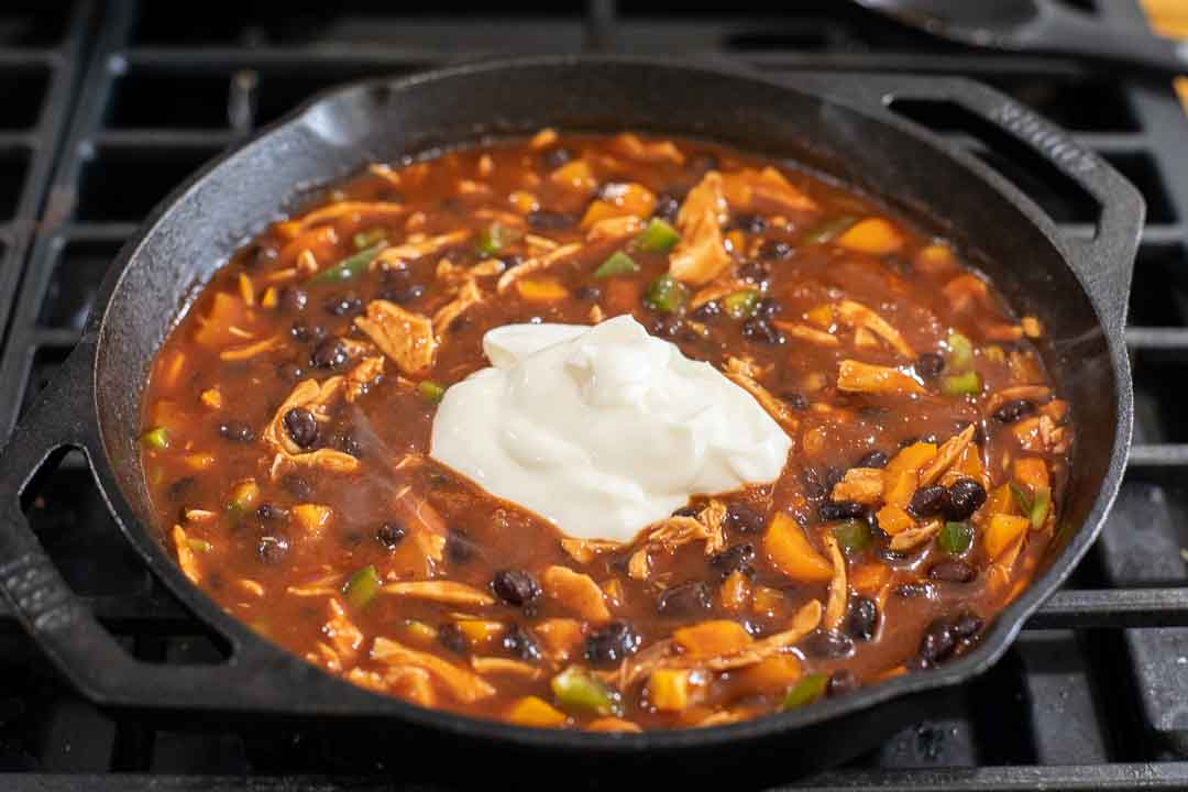 Sour cream on enchilada sauce, shredded chicken, diced peppers, and black beans.