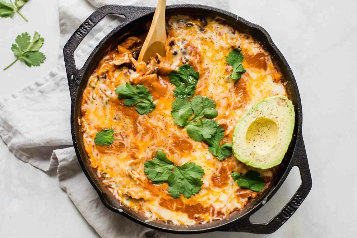 Top shot of Creamy Healthy Chicken Enchilada Skillet with a spoon and topped with cilantro and avocado.