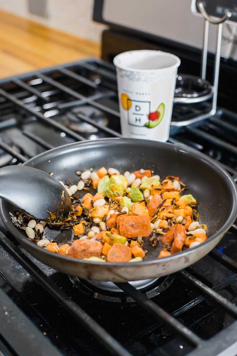 Cooking the ingredients of a Daily Harvest harvest bowl in a pan.