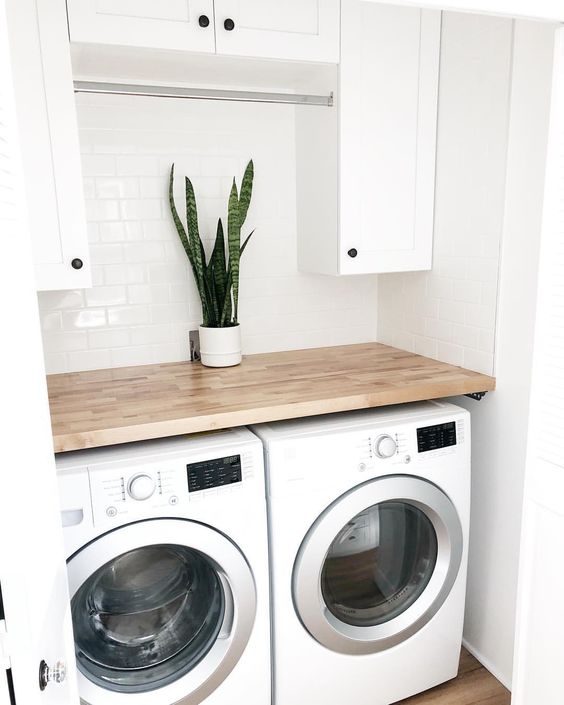 Angled shot of washer and dryer with butcher block and plant on top.