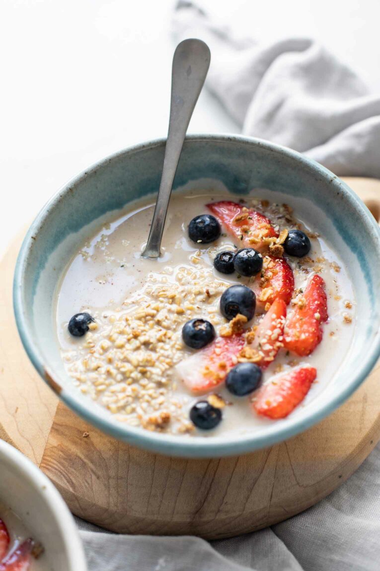 Angled shot of overnight steel cut oats in a blue bowl over a grey napkin.
