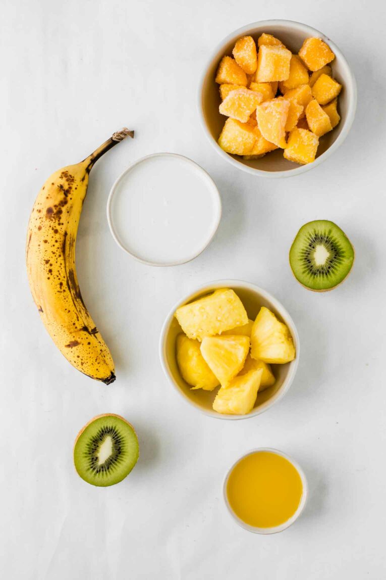 Ingredients for making a tropical smoothie on a white background.