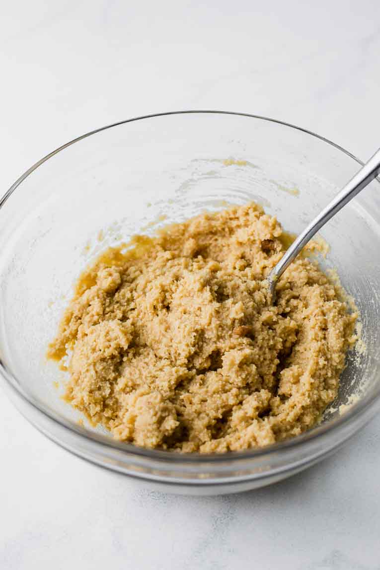 Dry and liquid ingredients for almond flour cookies in a mixing bowl.