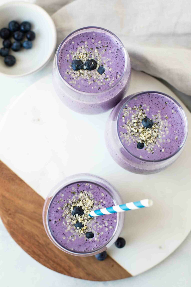 Top shot of 3 blueberry smoothies on a white marble board.