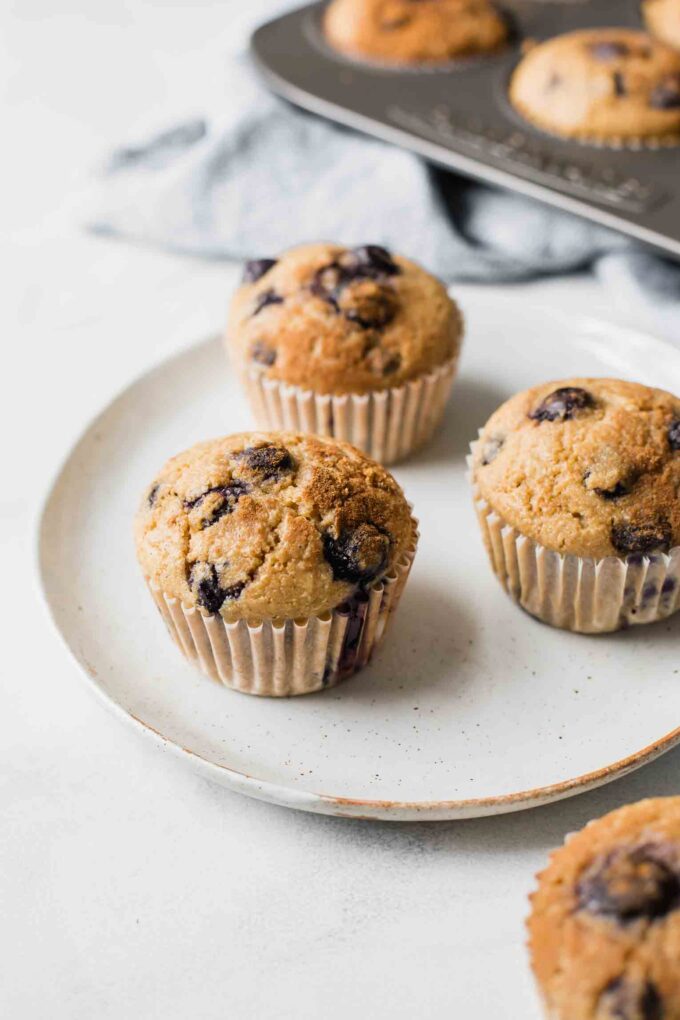 Angled shot of Blueberry Quinoa Muffins on a white plate with a napkin in the background.