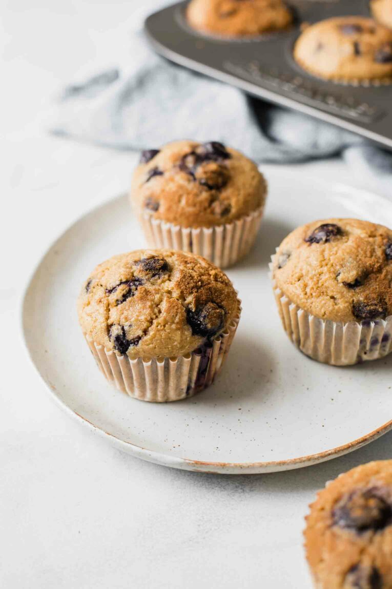 Angled shot of Blueberry Quinoa Muffins on a white plate with a napkin in the background.