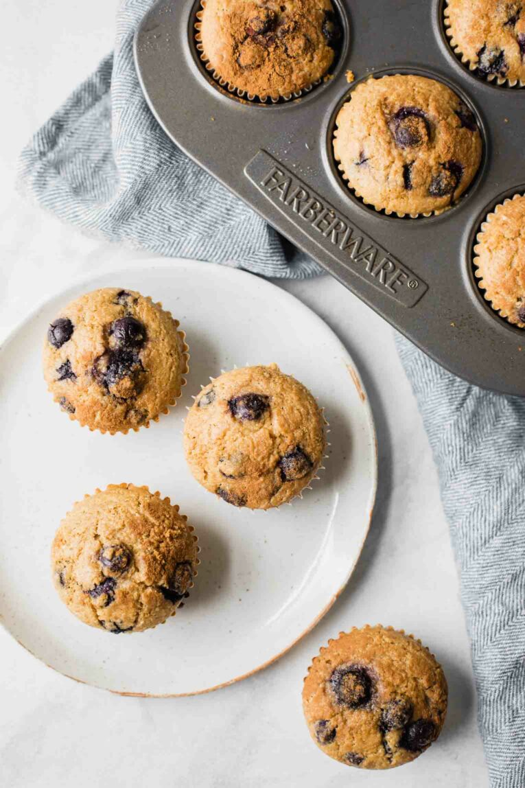 Top shot of Blueberry Quinoa Muffins on a white plate and in a muffin tin.