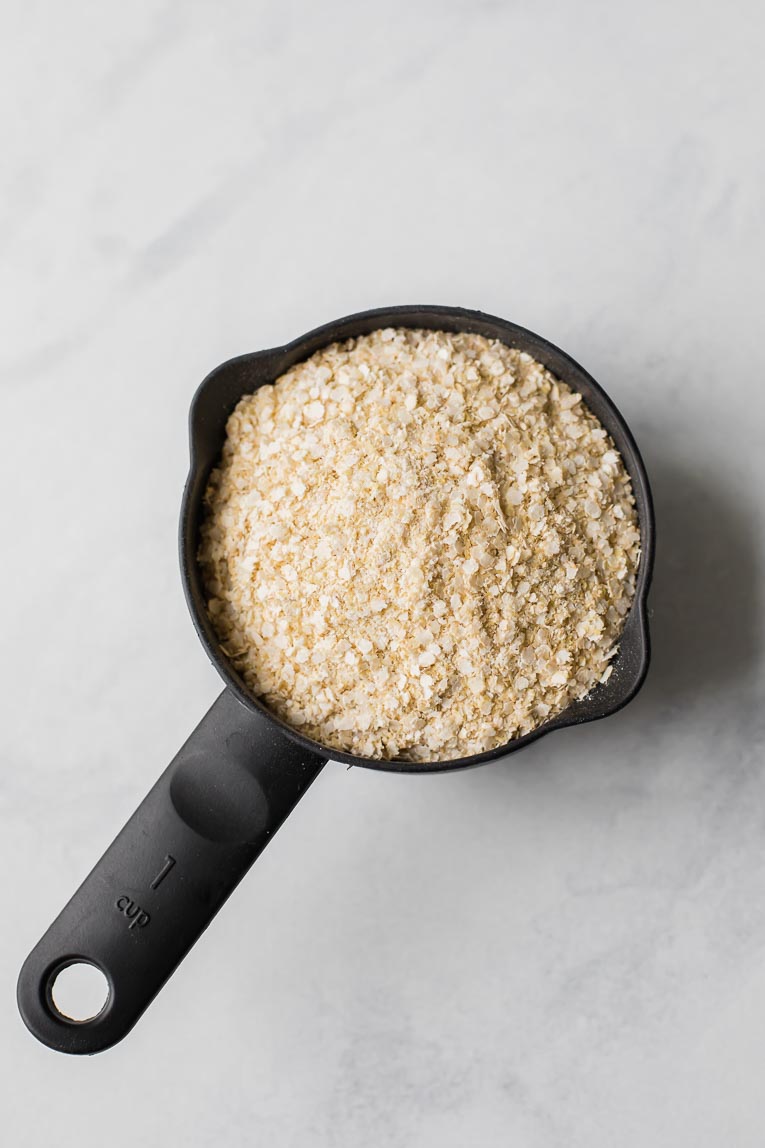 Quinoa flakes in a measuring cup.