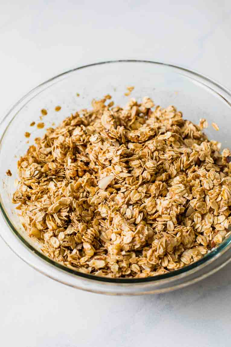 Mixed granola in a glass bowl before baking.