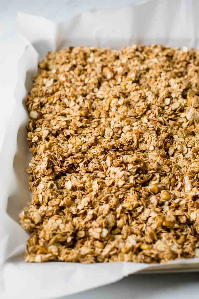 Raw granola on a baking sheet lined with parchment paper.