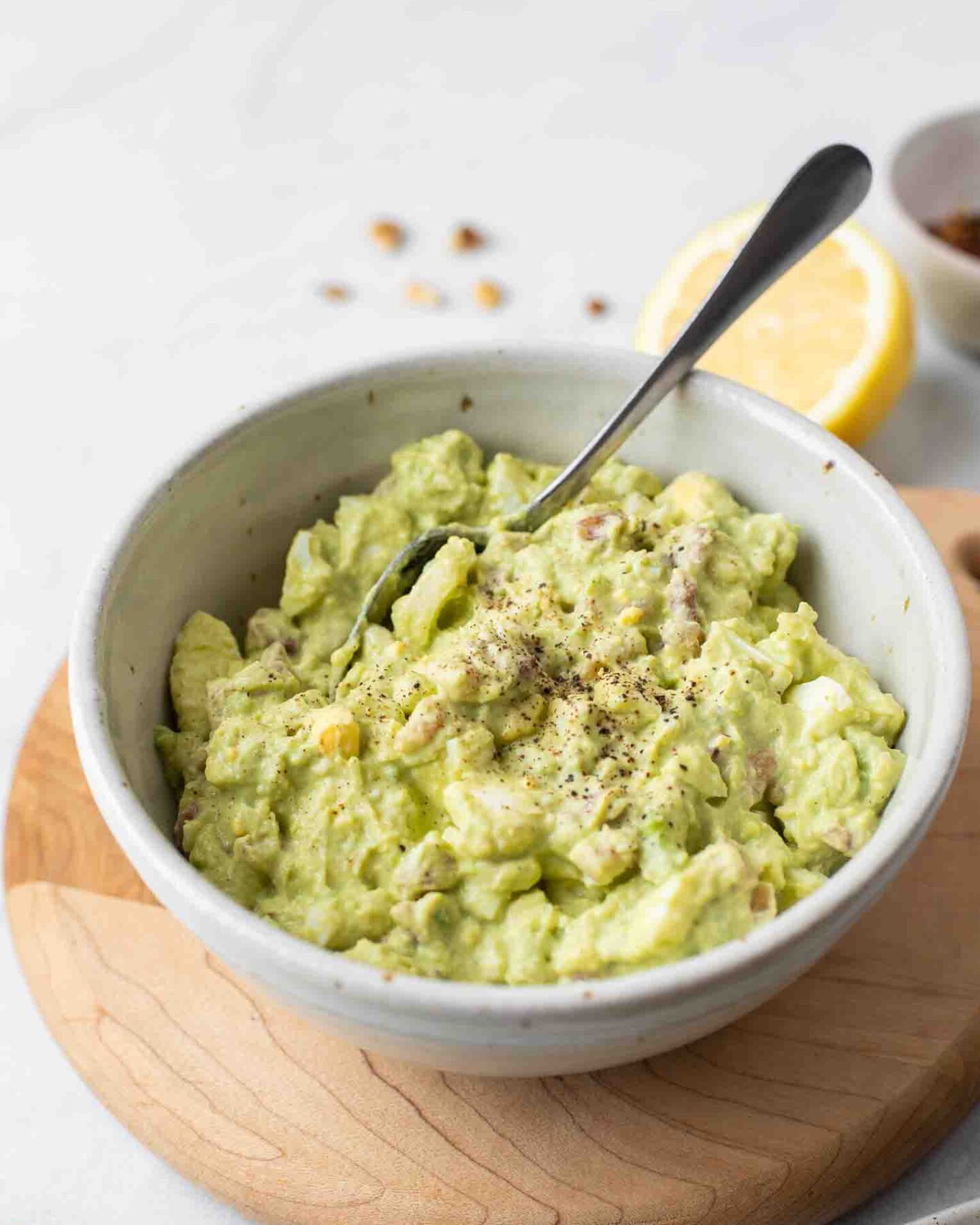 Healthy Avocado Egg Salad in a white bowl with a spoon.