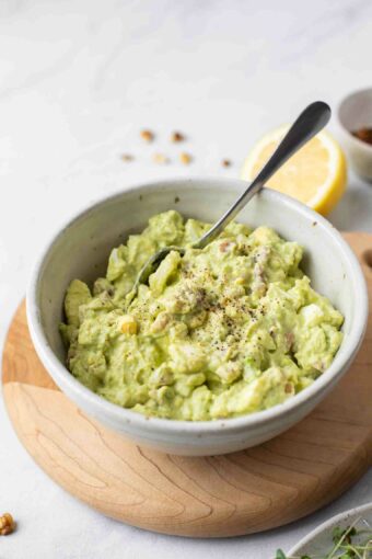 Healthy Avocado Egg Salad in a white bowl with a spoon.