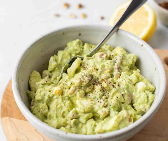 Healthy Avocado Egg Salad in a white bowl with a spoon.