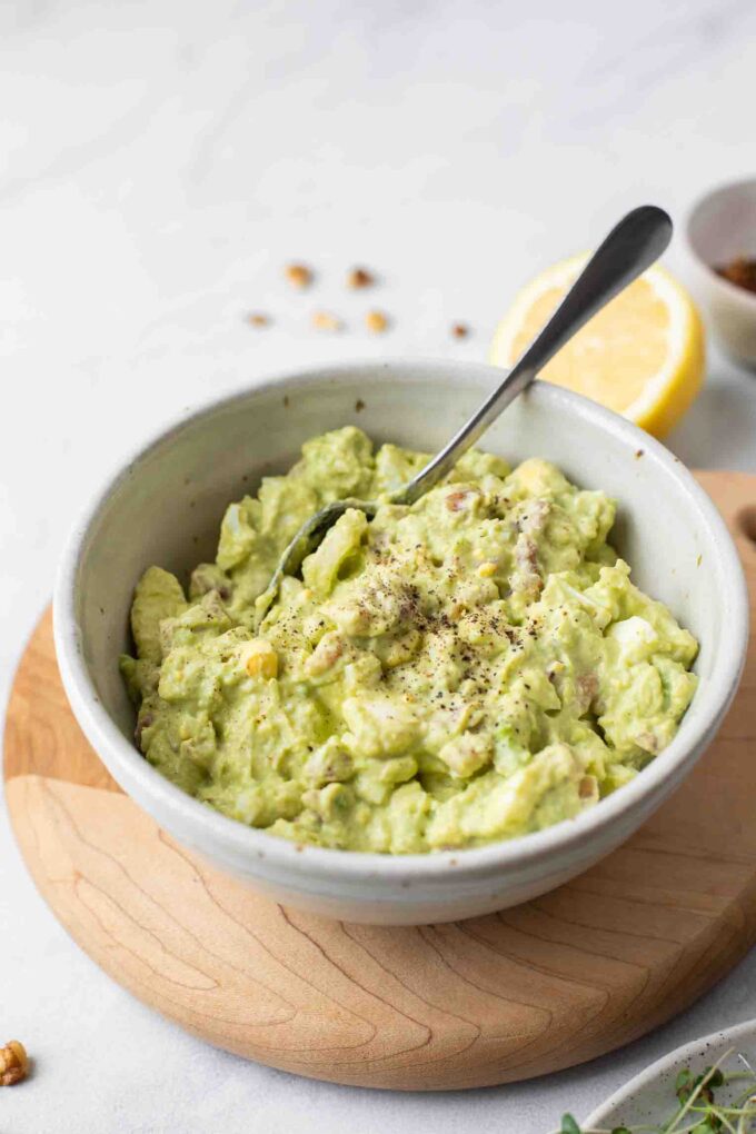 Healthy Avocado Egg Salad in a white bowl with a spoon.