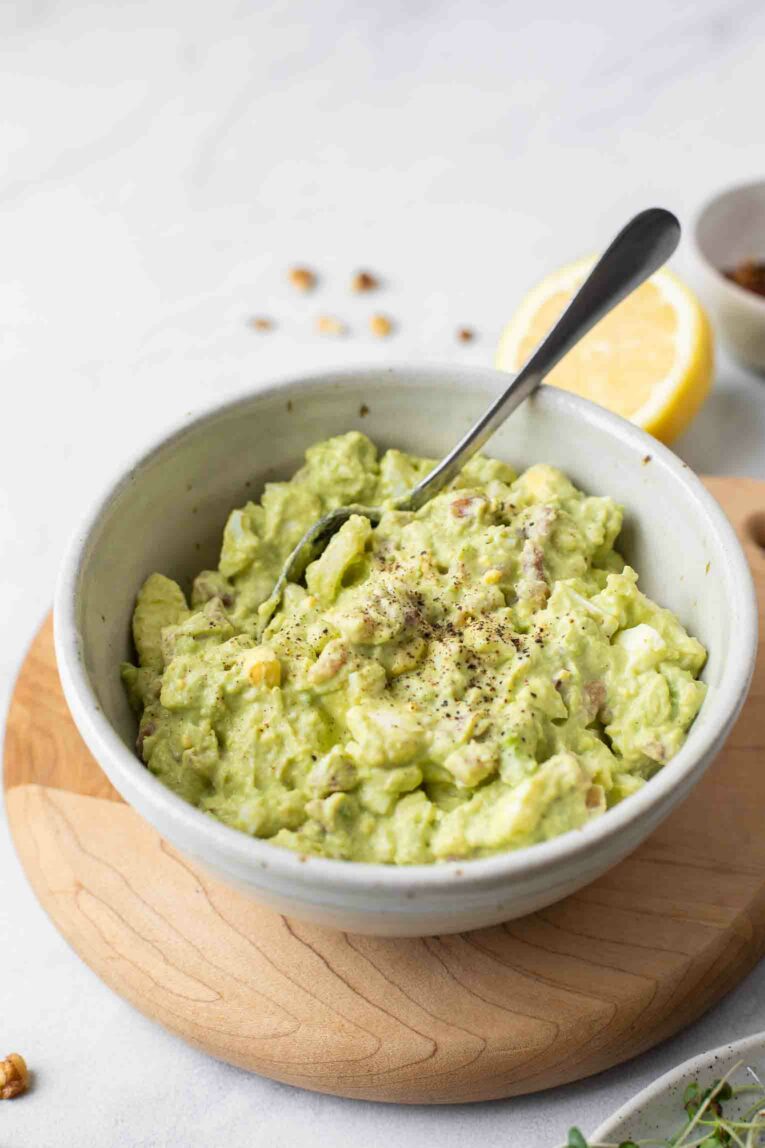 Healthy Avocado Egg Salad in a white bowl with a spoon.