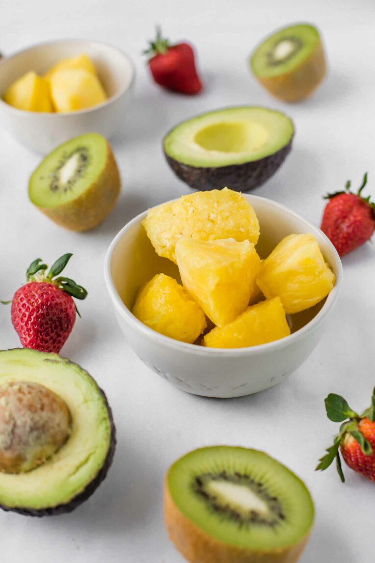 Angled shot of pineapple, kiwi, strawberries, and avocado.