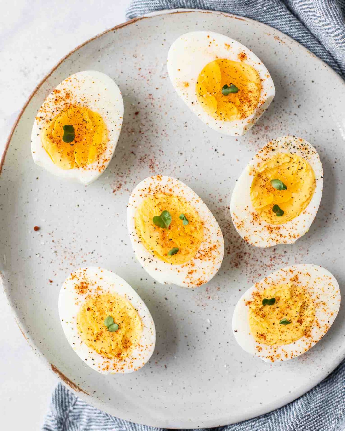 Close up of hard boiled eggs topped with salt, pepper, and paprika.