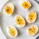 Close up of hard boiled eggs topped with salt, pepper, and paprika.