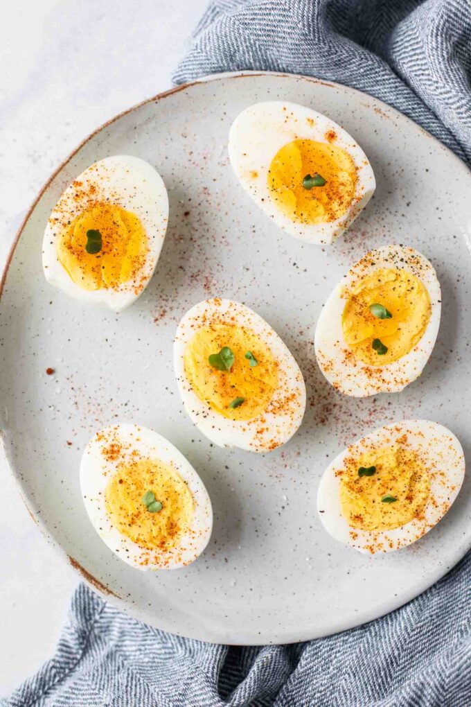 Close up of hard boiled eggs topped with salt, pepper, and paprika.