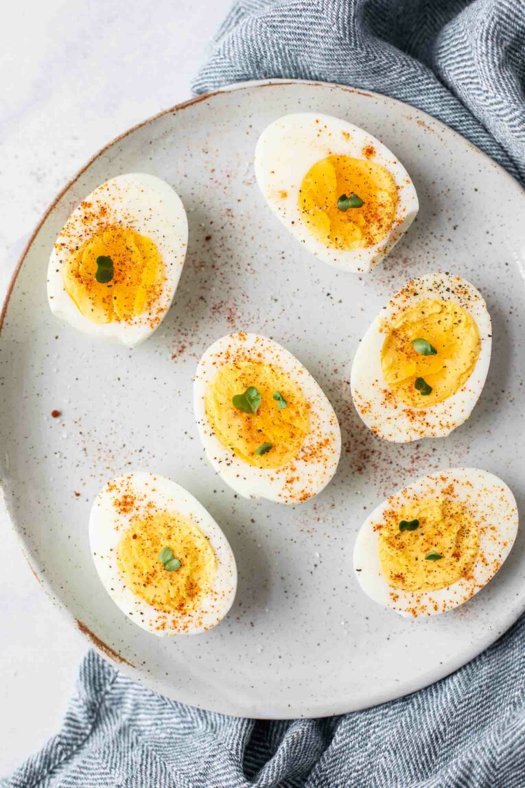Close up of hard boiled eggs topped with salt, pepper, and paprika.