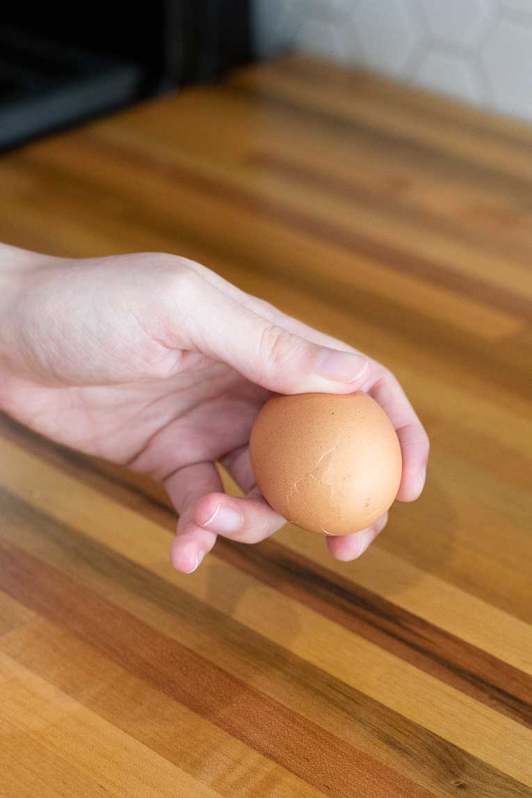 Egg being cracked on a countertop.
