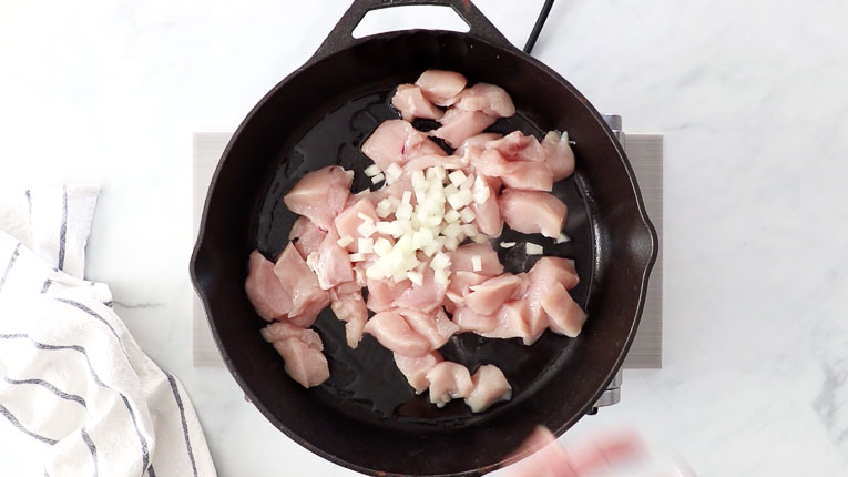 Chicken and onion cooking in a skillet.