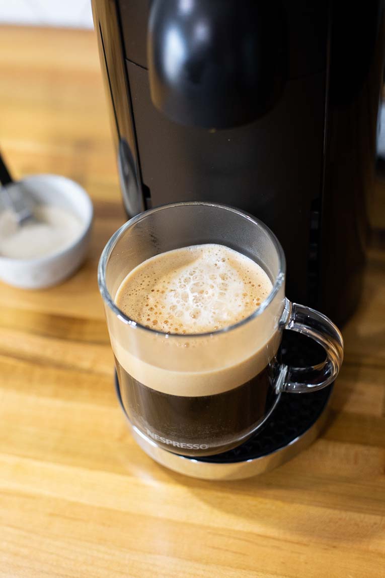 Coffee with foam in a glass mug.