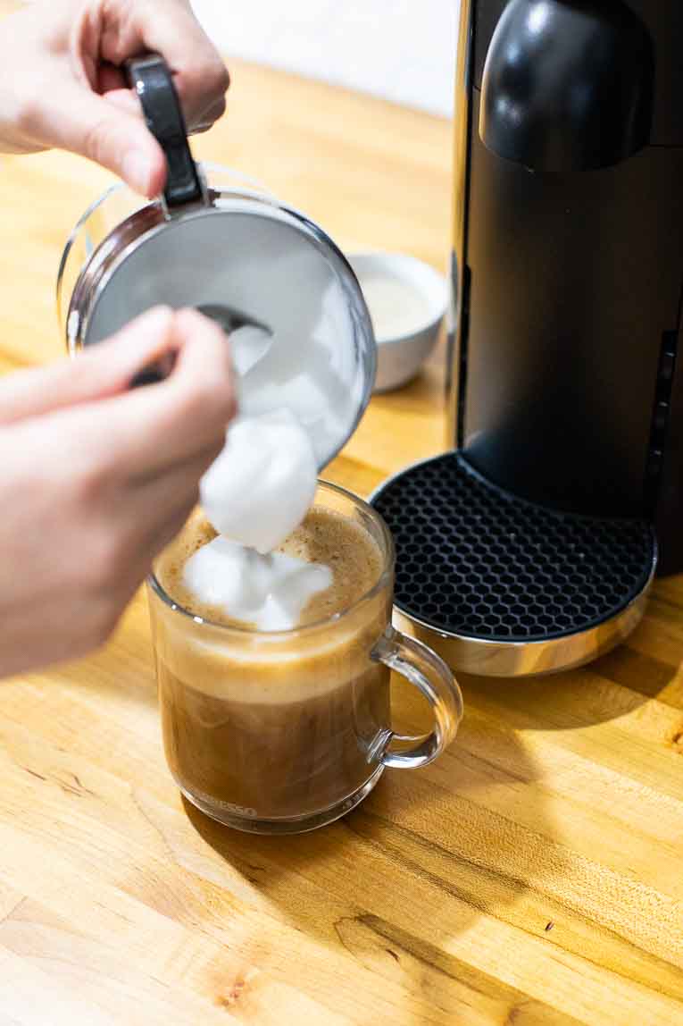 Pouring milk foam over a vanilla latte.