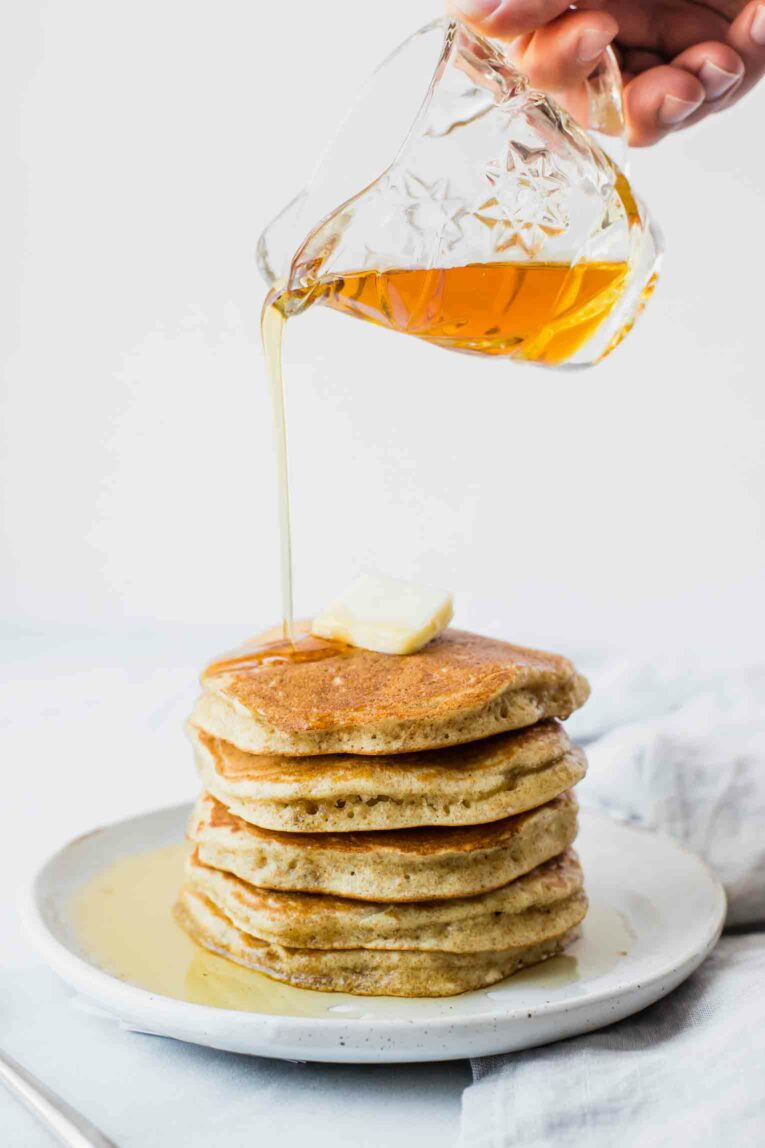 Syrup pouring on to a stack of sourdough pancakes.