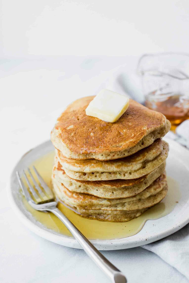 Angled shot of sourdough pancakes topped with butter on a plate.