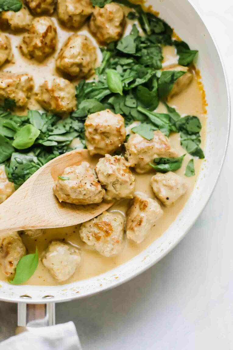Close up shot of Swedish meatballs on a wooden spoon.